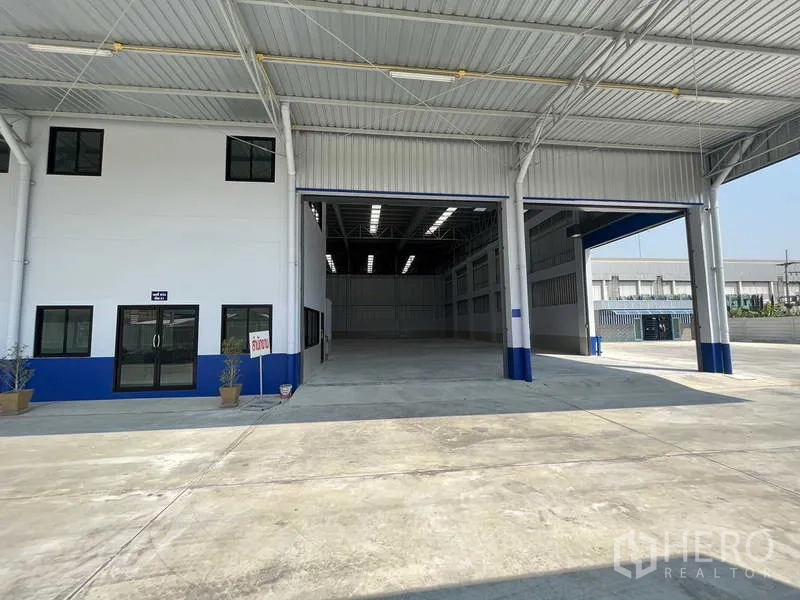 Warehouse for rent in Khlong Luang, Pathum Thani - Front of modern warehouse with wide covered loading area and large entry bays.