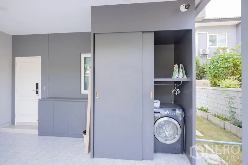 Detached House for sale in Prawet, Bangkok - Covered carport with built-in storage and a laundry area with washing machine.