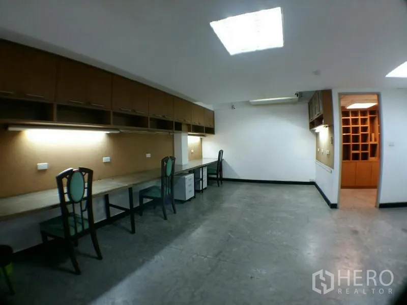 办公空间 出租在Phra Khanong, Bangkok - 曼谷Phra Khanong开放式办公区，长条内置书桌、上方柜与工作灯。