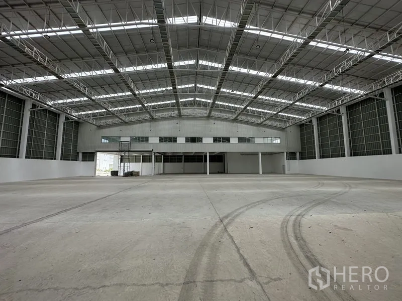 工厂 出租在Pathum Thani - 厂房地面有轮胎印，面向夹层与装卸区。