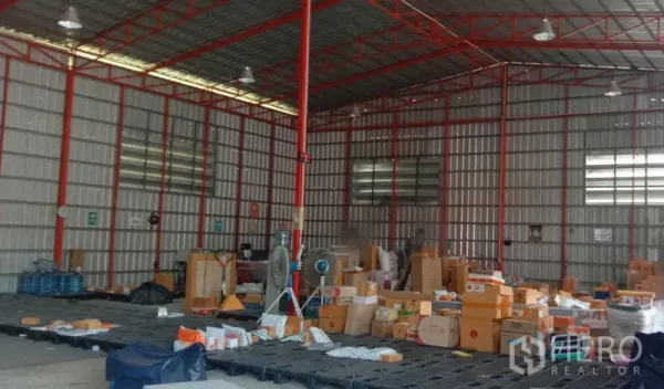 Warehouse for rent in Khlong Sam Wa, Bangkok - Warehouse interior featuring a red steel frame, high ceiling, ventilation panels, and parcels on plastic pallets.