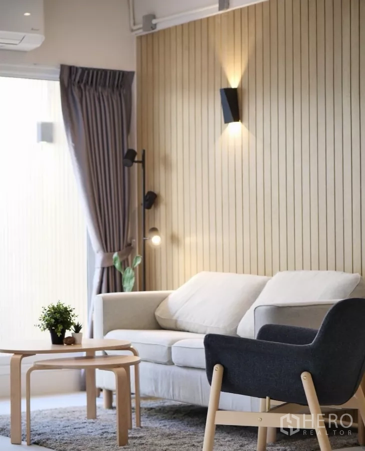Townhouse for rent or sale in Watthana, Bangkok - Cozy sofa corner with wood-slat accent wall and layered wall lights.