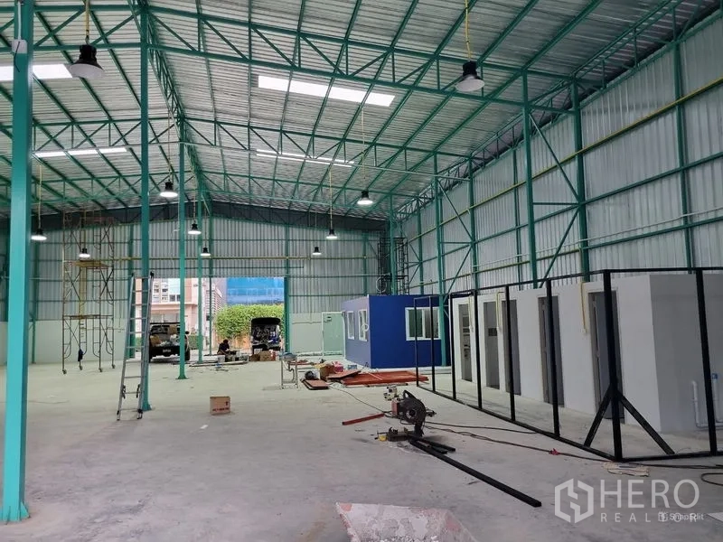 Warehouse for rent in Saphan Sung, Bangkok - Spacious high-ceiling warehouse interior with steel trusses, skylights, bright lighting and modular office rooms.