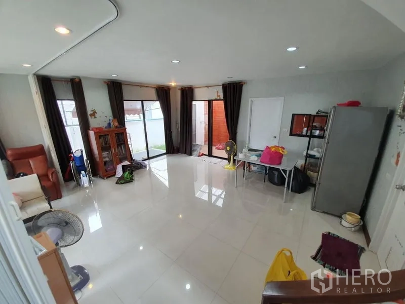 Detached House for sale in Samut Prakan - Spacious open-plan living room with glossy tile floors and sliding doors to the garden.