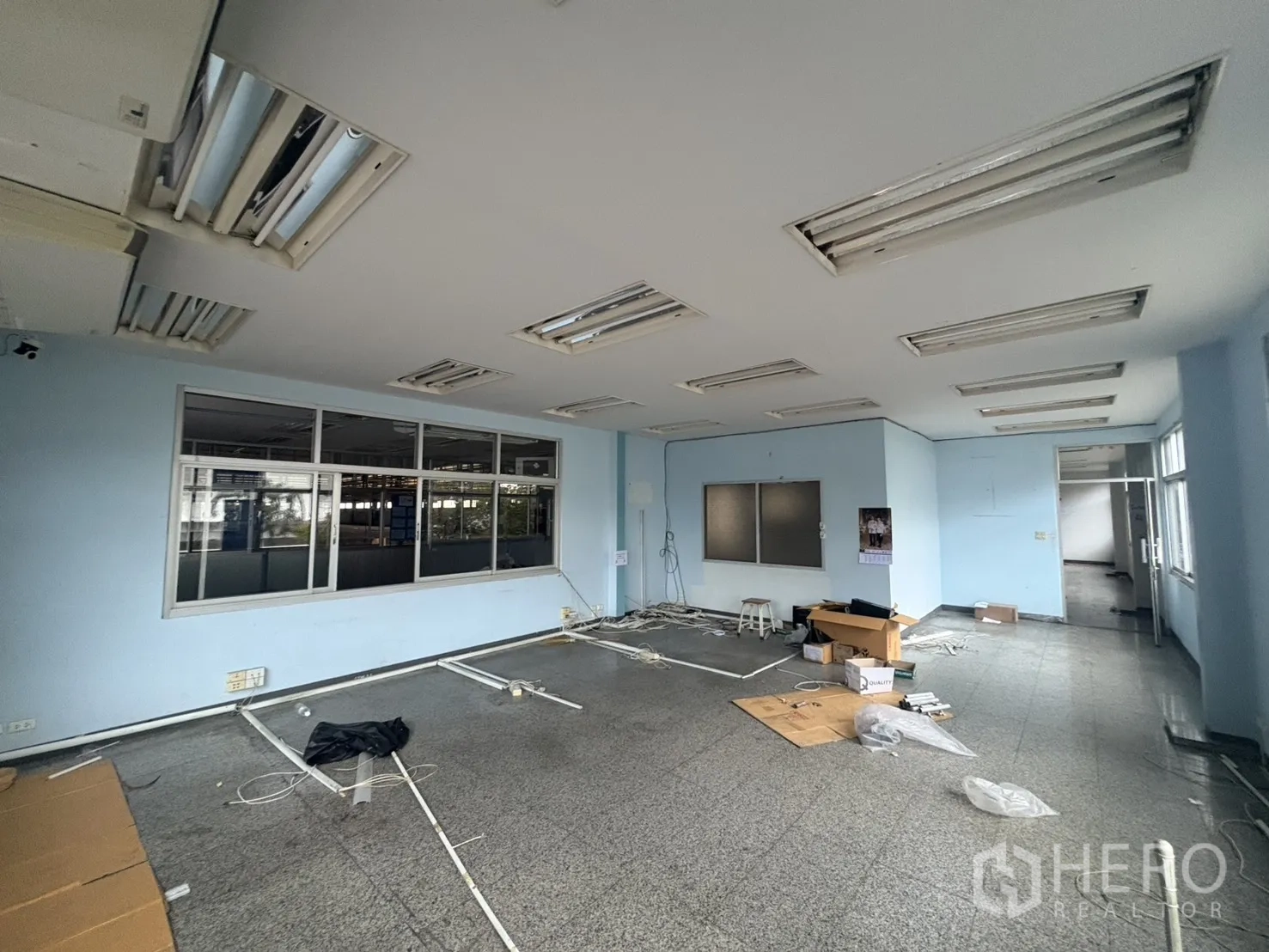 Factory for rent in Khlong Toei, Bangkok - Ground-floor office space with large windows and stone flooring during renovation.