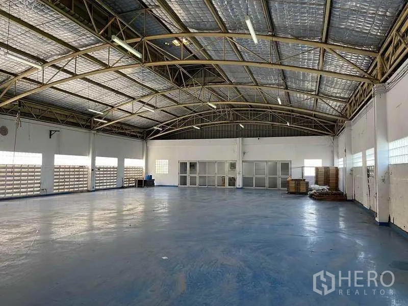 Factory for rent in Phra Samut Chedi, Samut Prakan - Clean warehouse bay with blue epoxy floor, windows and sliding doors.