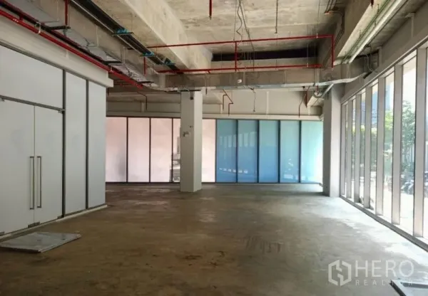 Retail Space for rent in Watthana, Bangkok - Corner view of the retail space showing central column, double doors, and frosted glass panels with abundant natural light.