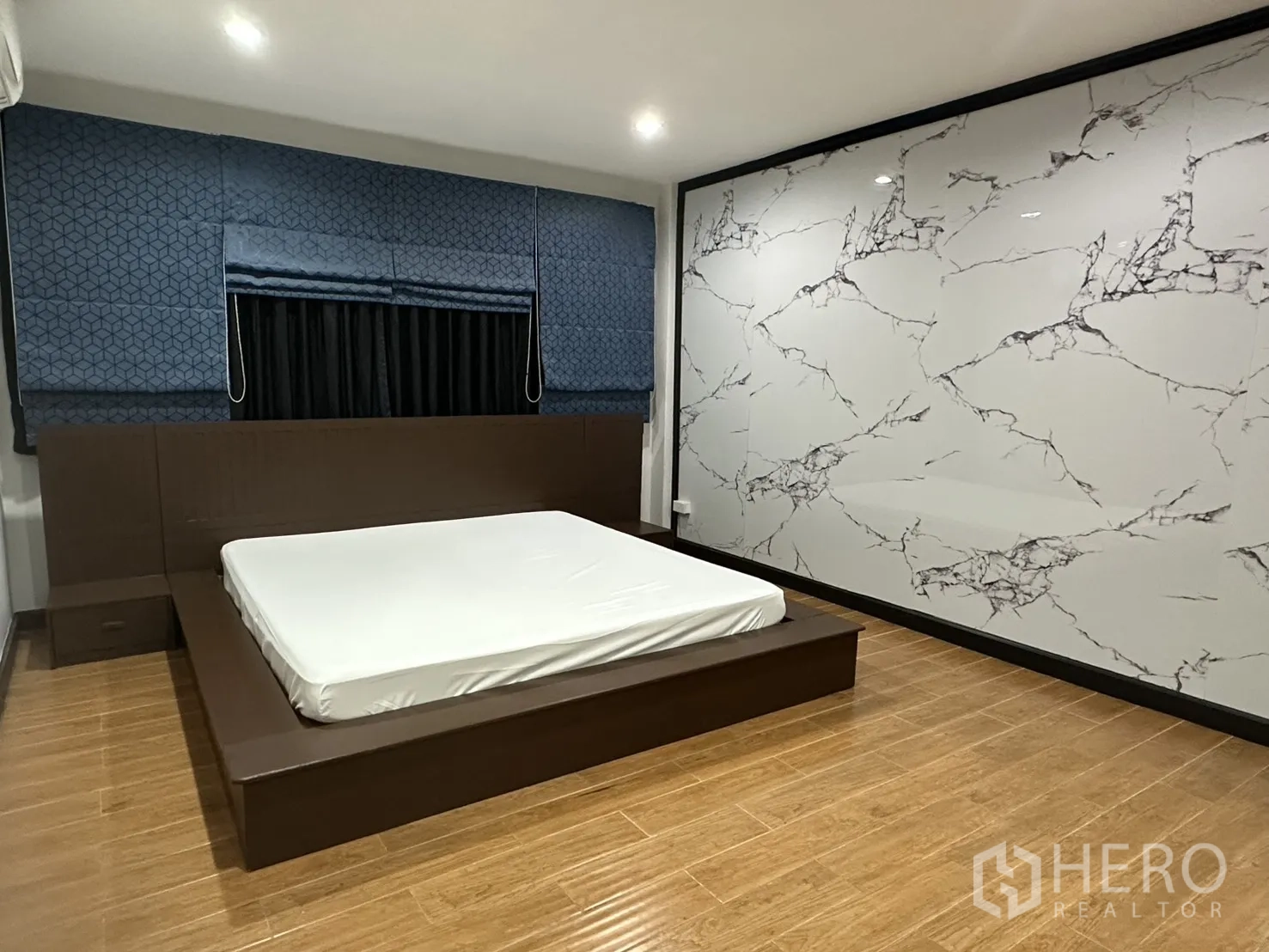 Home Office for rent in Khlong Toei, Bangkok - Spacious bedroom with platform bed and a large marble-effect feature wall.