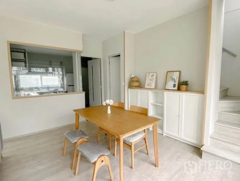 Detached House for rent in Prawet, Bangkok - Dining corner with wooden table beside a serving window to the kitchen.