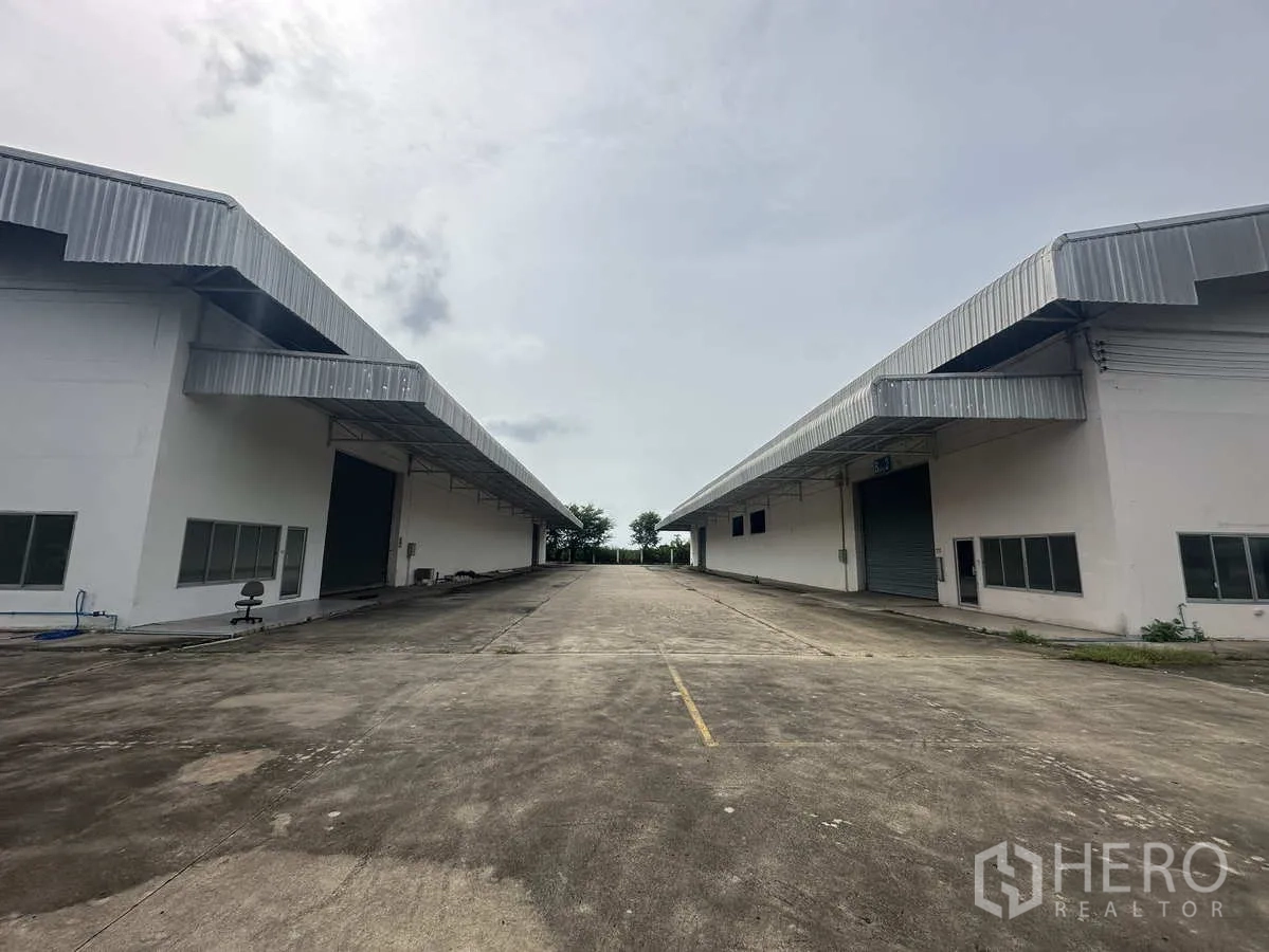 Warehouse for rent in Phra Nakhon Si Ayutthaya - Two warehouse buildings facing a broad driveway with covered loading bays for truck access.