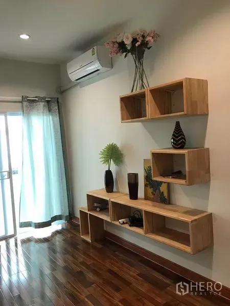 Townhouse for rent or sale in Phra Khanong, Bangkok - Wall-mounted wooden shelves, split air conditioner and sliding glass door with curtains.