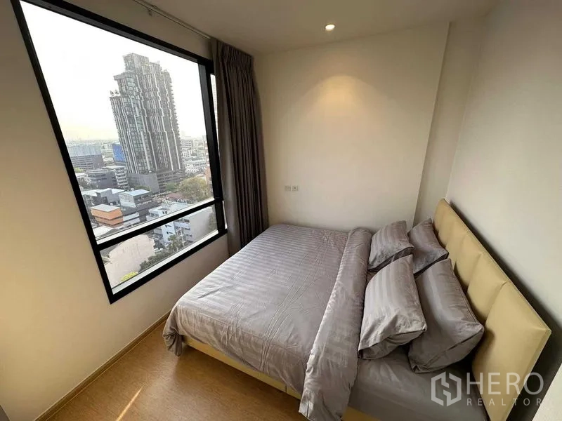 Condominium for sale - Second bedroom with big window, double bed and gray linens facing the city.