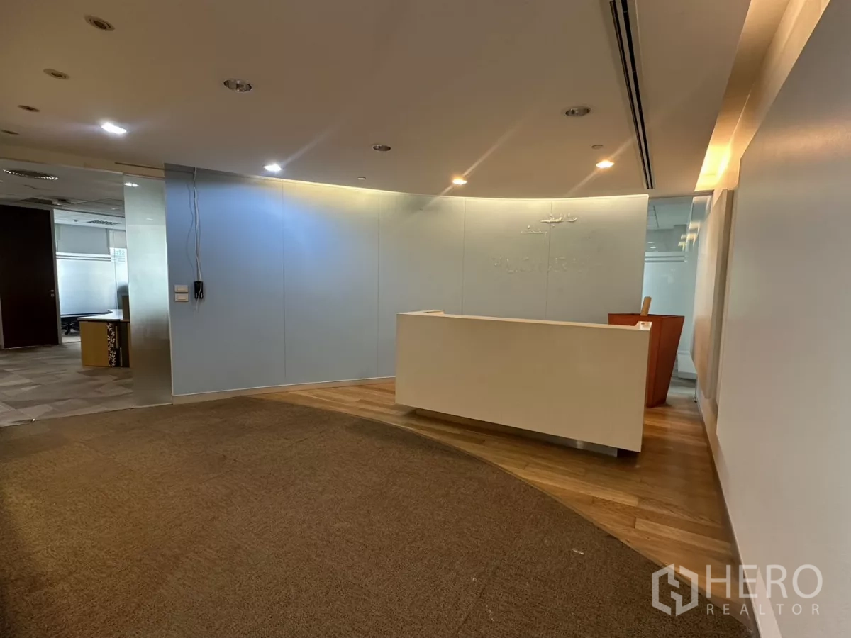Office Space for rent in Watthana, Bangkok - Reception area with curved carpet, wooden flooring and a white front desk in a modern office.