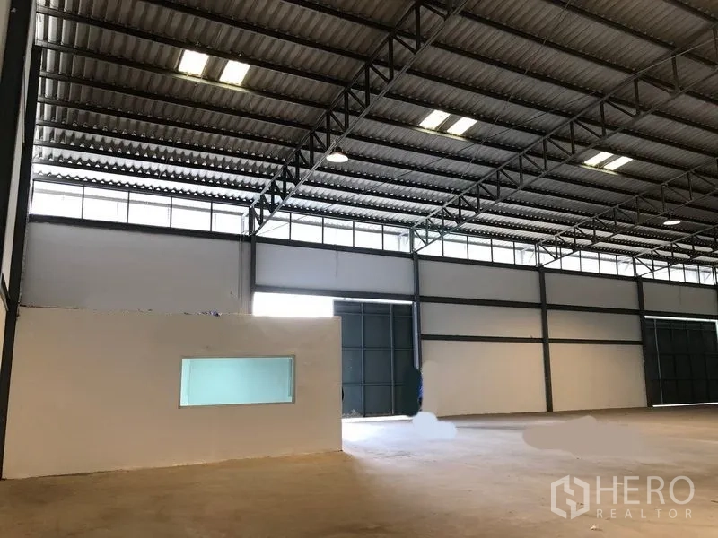 Warehouse for rent in Khlong Luang, Pathum Thani - Side exterior of the warehouse with oversized sliding doors and a concrete loading apron.