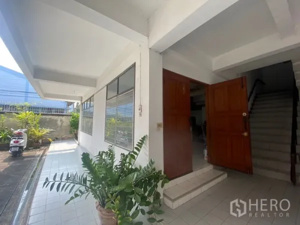 Home Office for rent in Khlong Toei, Bangkok - Main entrance with double wooden doors and large windows along a tiled walkway.