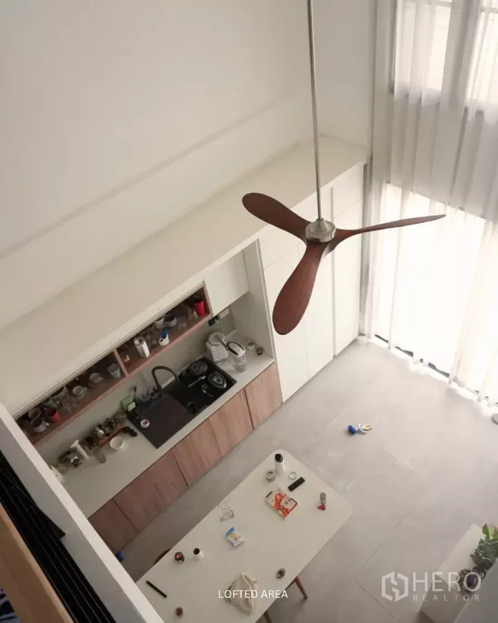 Townhouse for rent in Suan Luang, Bangkok - Aerial view of a double-height kitchen with white cabinetry, wood accents, island table, and full-height sheer curtains.