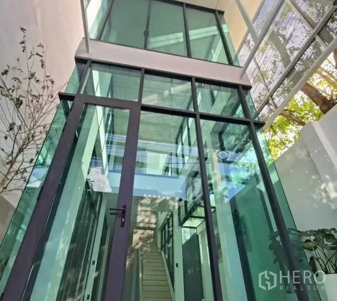 Home Office for rent in Suan Luang, Bangkok - Double-height glass atrium entrance with dark metal frames and stairway views.