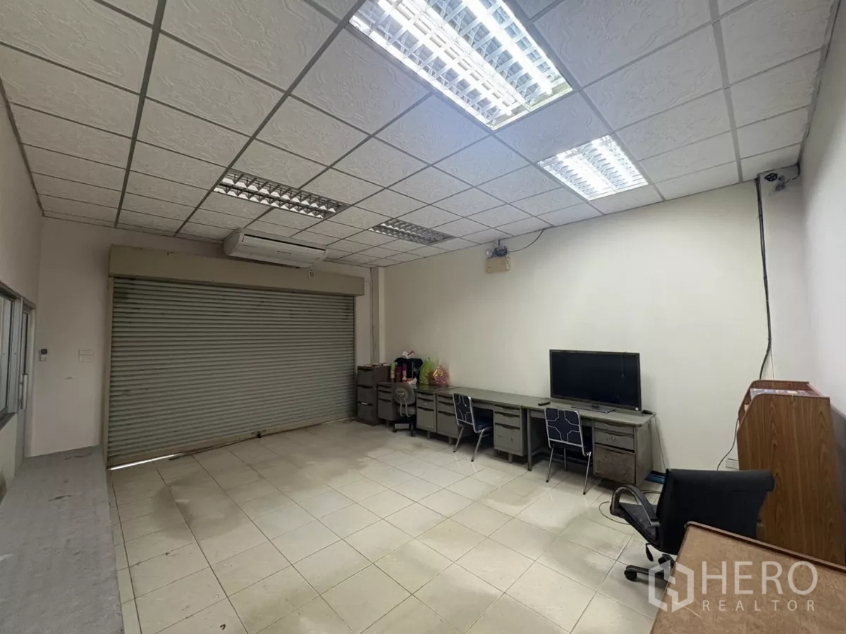 Warehouse for rent in Bang Phli, Samut Prakan - Ground-floor office with roller shutter, desks and air conditioner.