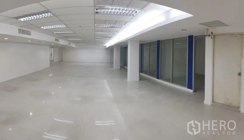 Office Space for rent in Chatuchak, Bangkok - Long office corridor-style space with glass rooms, white door, and tiled floors.