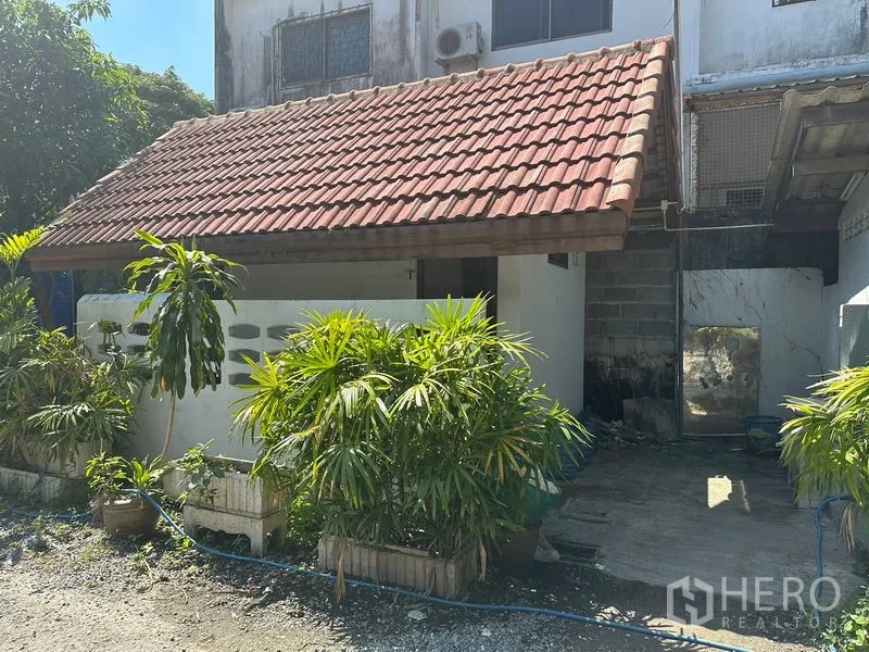 货栈 出租在Suan Luang, Bangkok - 现场小型办公室或门卫室，红瓦屋顶，周边绿植点缀。