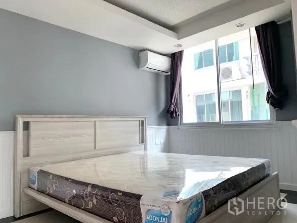 Condominium for rent in Khlong Toei, Bangkok - Bedroom with large window, air conditioning and light wood bed frame.