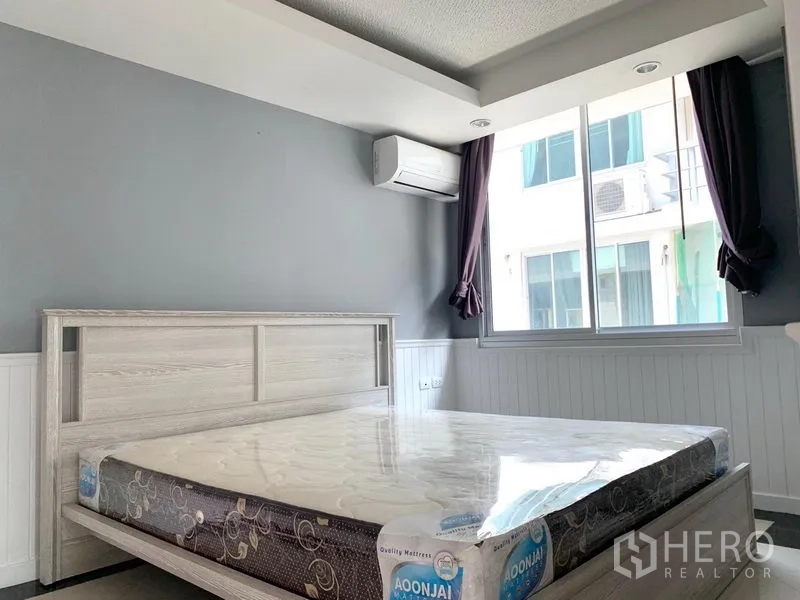 Condominium for rent in Khlong Toei, Bangkok - Bedroom with large window, air conditioning and light wood bed frame.