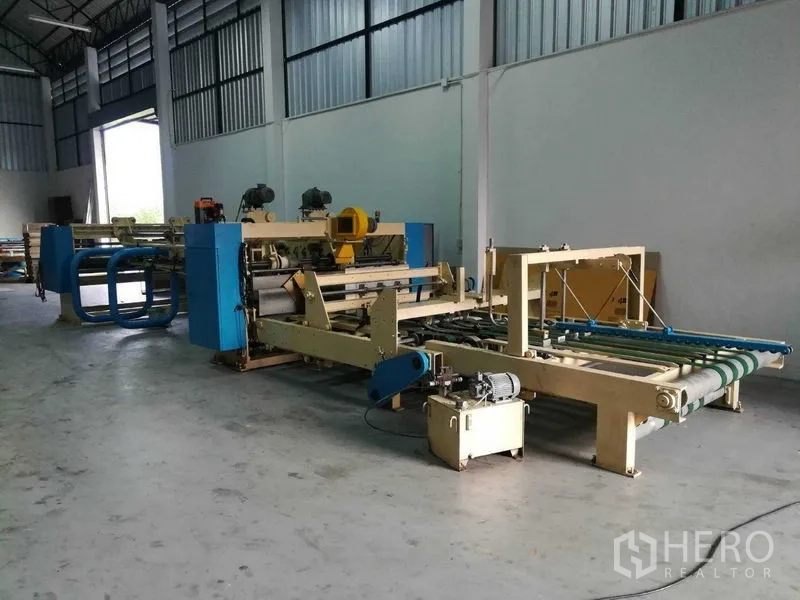 Factory for sale in Bang Len, Nakhon Pathom - Open factory floor with large machines and a wide loading door for access.