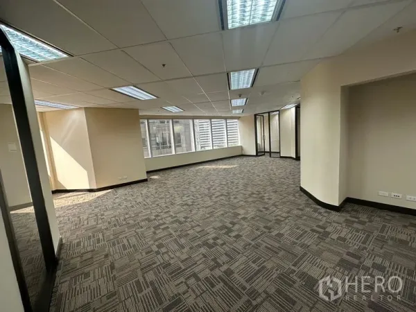 Office Space for rent - Bright open-plan office with large windows, ceiling lights and patterned carpet tiles.
