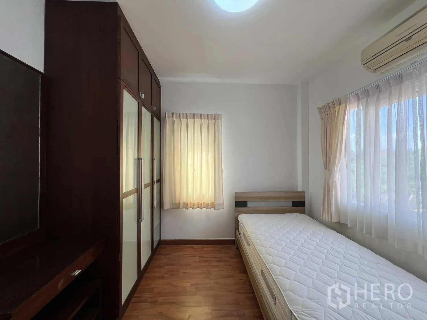 Detached House for rent in Bang Kapi, Bangkok - Bedroom with corner windows, bed and dresser letting in abundant light.