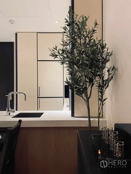 Condominium for rent in Khlong Toei, Bangkok - Kitchen corner detail with sleek sink, tall cabinetry and decorative indoor plant.