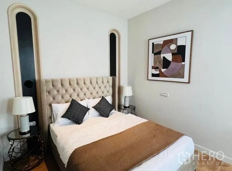 Detached House for rent or sale in Watthana, Bangkok - Guest bedroom with tufted headboard, side tables and modern wall art.