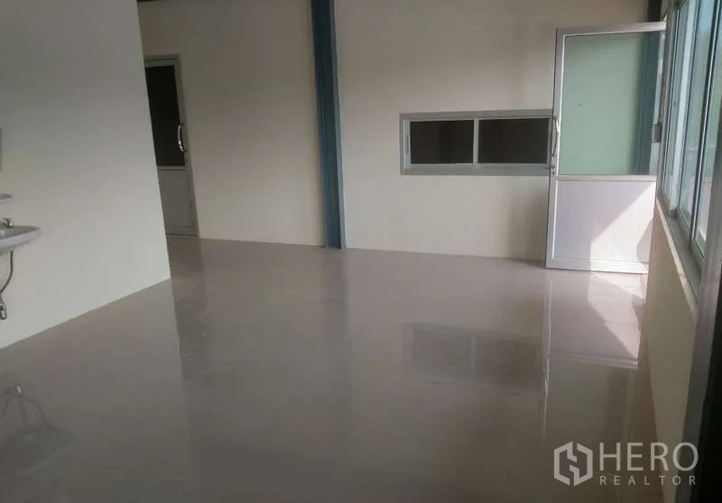 Factory for rent in Ban Phaeo, Samut Sakhon - Bright tiled office area with sink, windows, and a doorway to an internal room.