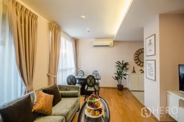 Condominium for rent or sale in Watthana, Bangkok - Open-plan lounge and dining room with soft lighting, air conditioning and wooden flooring.