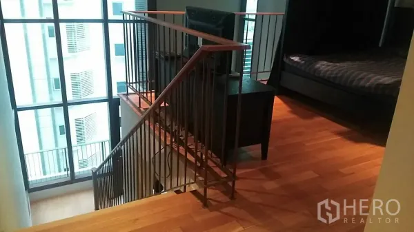 Condominium for sale in Khlong Toei, Bangkok - Duplex mezzanine level with stairs and floor-to-ceiling windows.