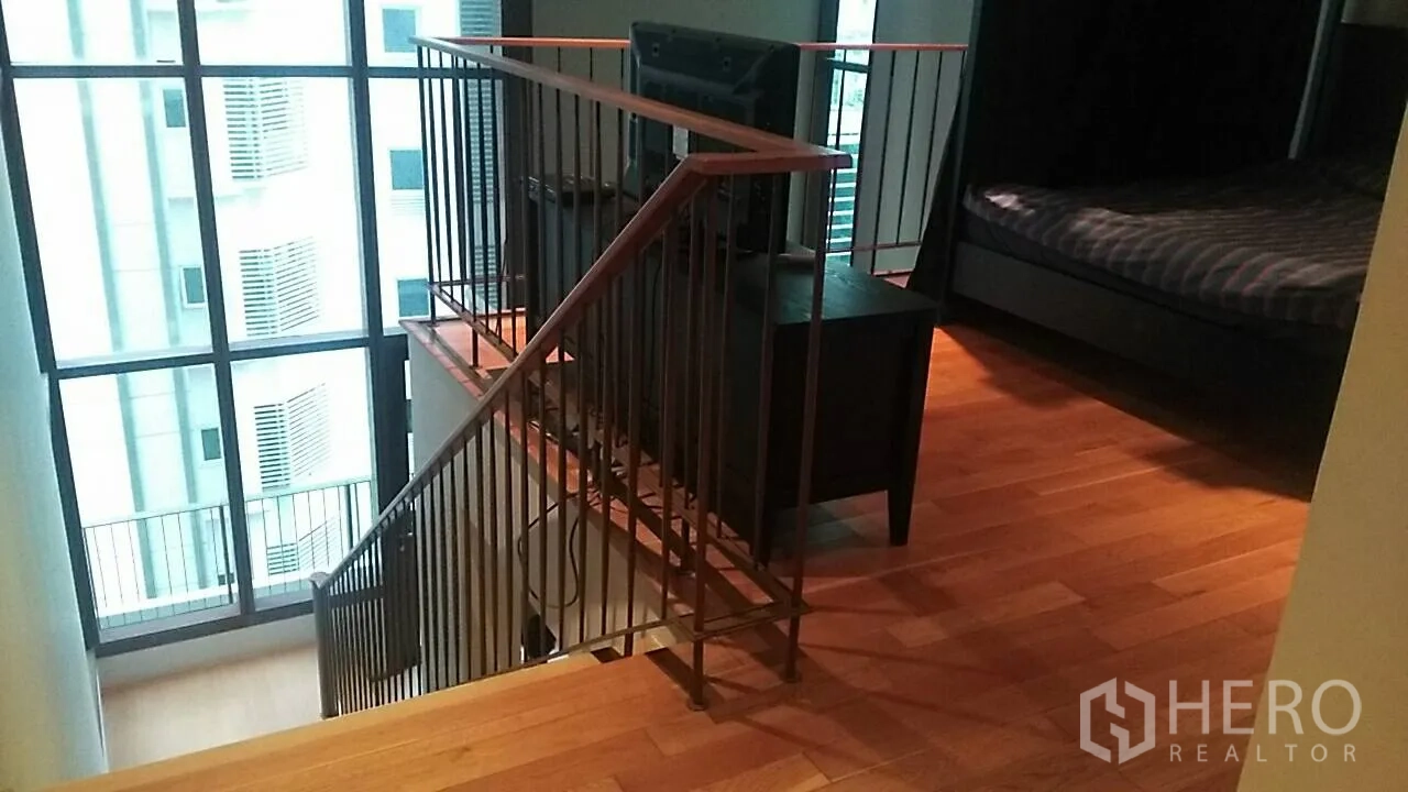 Condominium for sale in Khlong Toei, Bangkok - Duplex mezzanine level with stairs and floor-to-ceiling windows.