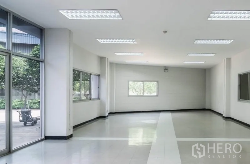 Factory for rent in Mueang Samut Sakhon, Samut Sakhon - Ground-floor office area with large windows and a glass entry facing the landscaped yard.