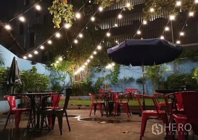 Retail Space for rent in Watthana, Bangkok - Garden courtyard at night with string lights and red metal chairs and tables.