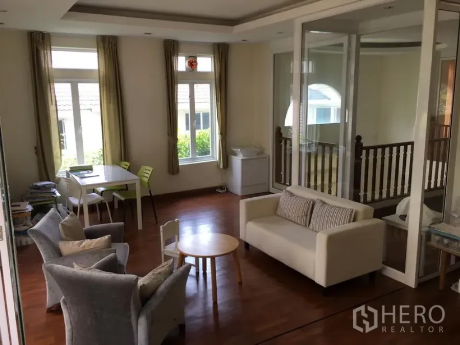 Townhouse for sale in Huai Khwang, Bangkok - Upper-floor lounge with wood flooring, large windows and a sliding glass partition.