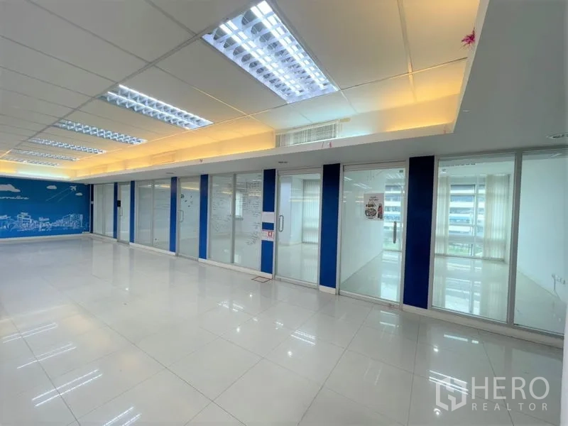Office Space for rent in Chatuchak, Bangkok - Compact private office with window wall, wood-look floor, and graphic walls.