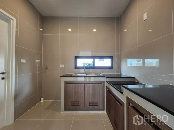 Detached House for sale in Lam Luk Ka, Pathum Thani - Modern Thai kitchen with built-in cabinets, countertops and a slim horizontal window.