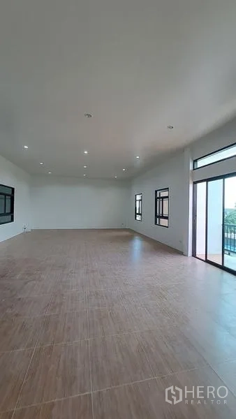 Warehouse for rent in Lam Luk Ka, Pathum Thani - Bright open-plan office room with wood-look tile flooring, windows and a balcony door.