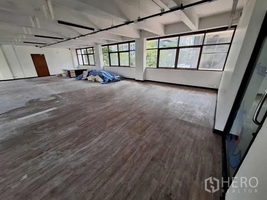 Office Space for rent in Watthana, Bangkok - Open-plan workspace with glass entry door and long corner windows.