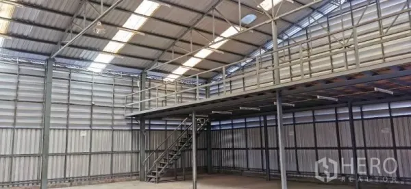 Warehouse for rent in Huai Khwang, Bangkok - High-clearance steel-frame warehouse interior with mezzanine level and staircase.
