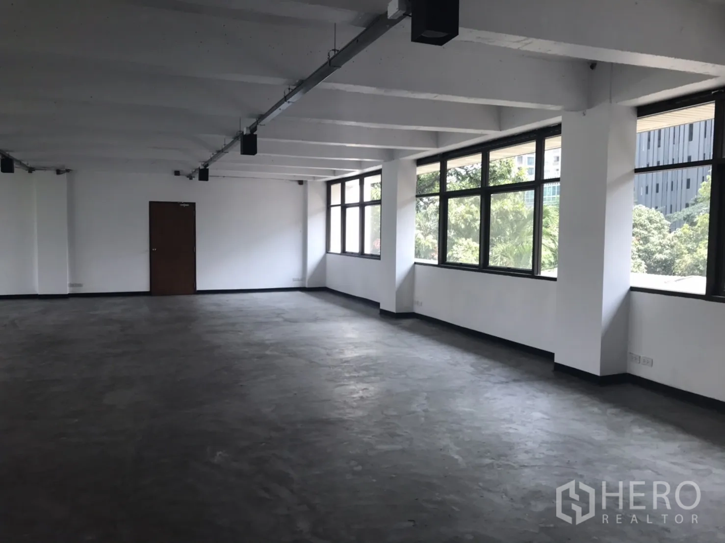 Office Space for rent in Khlong Toei, Bangkok - Empty open‑plan office with wide windows, polished concrete floor and green city views.