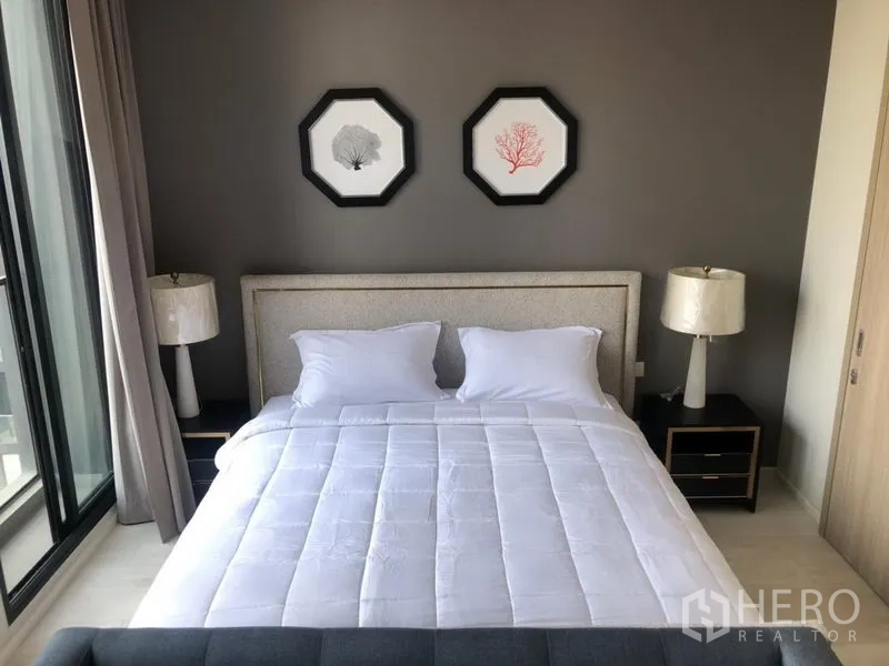 Condominium for rent in Pathum Wan, Bangkok - Cozy bedroom with large bed, bedside lamps and access to natural light.