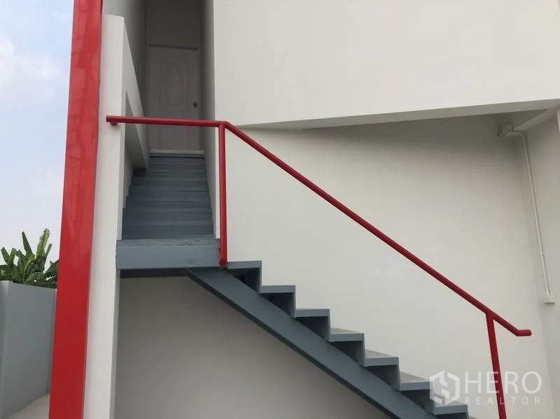 Warehouse for sale in Khlong Luang, Pathum Thani - External staircase with red handrail leading to an upper office door.