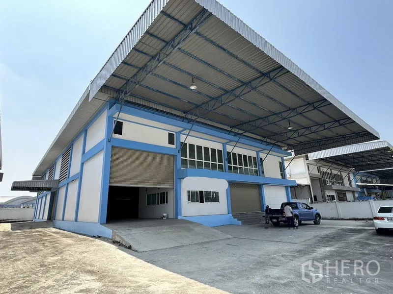 工厂 出租在Bang Bo, Samut Prakan - 蓝白色工厂外观，超大金属雨棚、装卸坡道与卷帘门。