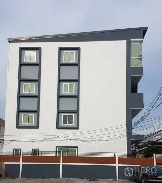 สำนักงานที่บ้าน ขายในLat Phrao, Bangkok - มุมมองด้านข้างของอาคารสีขาวทรงร่วมสมัย พร้อมหน้าต่างกรอบเข้มและหลังคาลาด