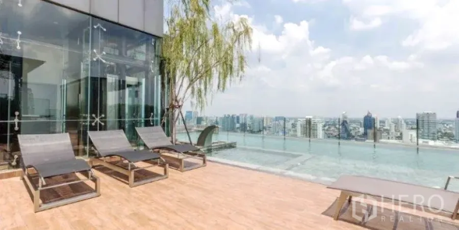 Condominium for rent or sale in Watthana, Bangkok - Rooftop infinity pool with sun loungers and panoramic Bangkok skyline at a modern Watthana condo.