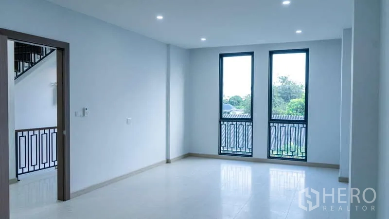 Detached House for rent or sale in Suan Luang, Bangkok - Spacious room with two tall windows and Juliet balconies overlooking greenery